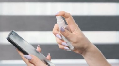 Kadın şeker kutusunu itiyor ve akıllı telefondan antiseptik sıkıyor. Akıllı Telefon Ekran Dezenfeksiyonu. Hastalık önleyici.