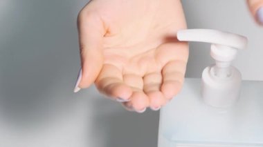 Kadın şeker kutusuna basıyor ve antiseptiği sıkıyor. Ellerini alkol çözeltisiyle yıka. El dezenfeksiyonu. Hastalık önleme