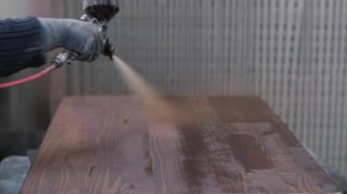 Katılımcı verniği bir polis memurunun yardımıyla ahşap bir masa üstüne uygular. Marangozluk atölyesinde çalışıyorum. Mobilya üretimi.