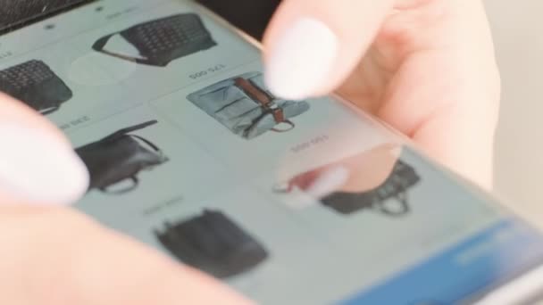 La fille achète le sac d'une femme dans une boutique en ligne avec un téléphone portable. Shopping en ligne. Shopping mobile Restez à la maison. Gros plan 