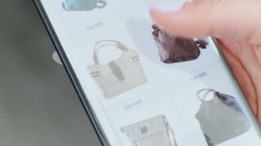 Kız çevrimiçi bir dükkandan cep telefonu olan bir kadın çantası alıyor. İnternetten alışveriş. Mobil Alışveriş Evde Kal. Kapat.