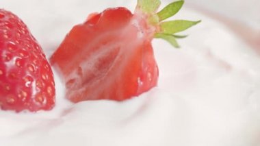 Yoğurda bandırılmış taze çilekler. Kapatın. Kameranın dairesel hareketi
