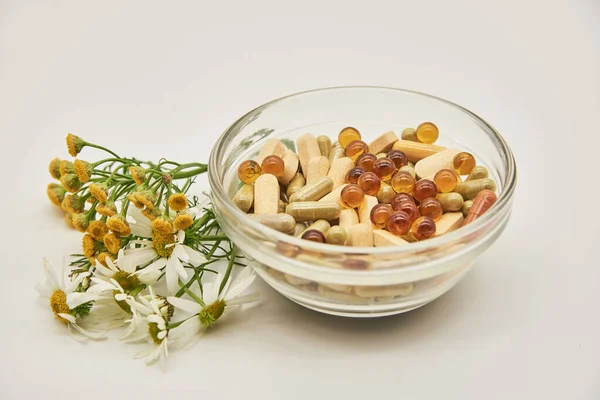 Medicamentos alternativos.En un recipiente de vidrio hay cápsulas y tabletas, junto a hierbas medicinales. . —  Fotos de Stock