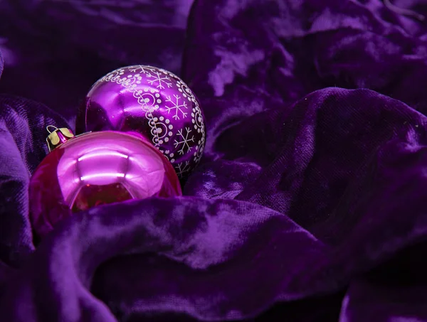 밝은 크리스마스 공 두 개가 짙은 자주색 벨벳 위에 놓여 있다. 크리스마스 배경 — 스톡 사진