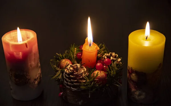 Three burning Christmas candles on a dark background. — Stock Photo, Image