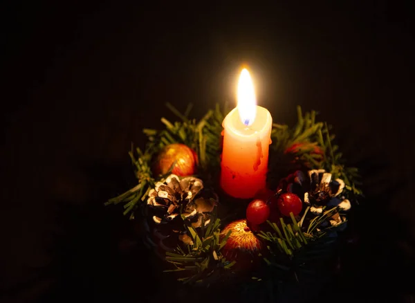 Uma vela em uma grinalda de Natal em um fundo escuro . — Fotografia de Stock