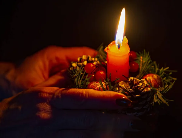 Χέρια ηλικιωμένης γυναίκας που κρατάει χριστουγεννιάτικο κερί. — Φωτογραφία Αρχείου