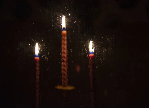 Three red candles burning in the darkness outside the window — Stock Photo, Image