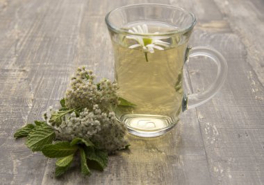 Ahşap zemin üzerinde bitki çayı olan şeffaf bir fincan..