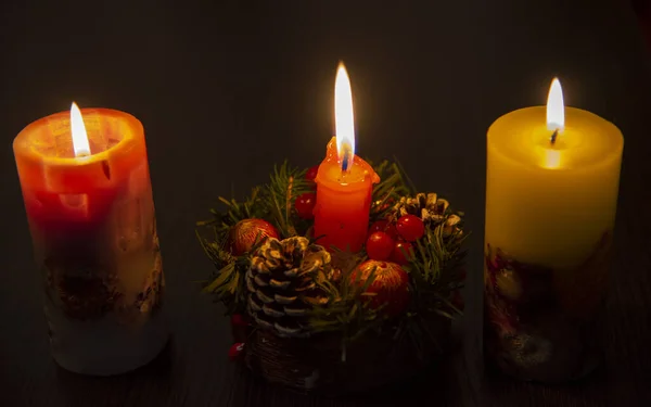 Tři hořící vánoční svíčky na tmavém pozadí. — Stock fotografie