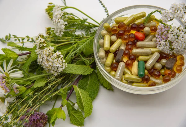 İçinde çeşitli kapsüller, tabletler, tıbbi ve aromatik otlar bulunan bir kase.. 
