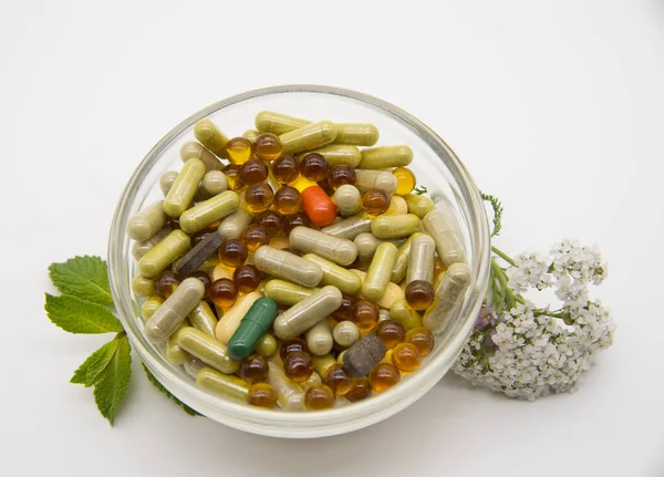 Чаша с различными капсулами и таблетками, лекарственными и ароматическими травами . — стоковое фото