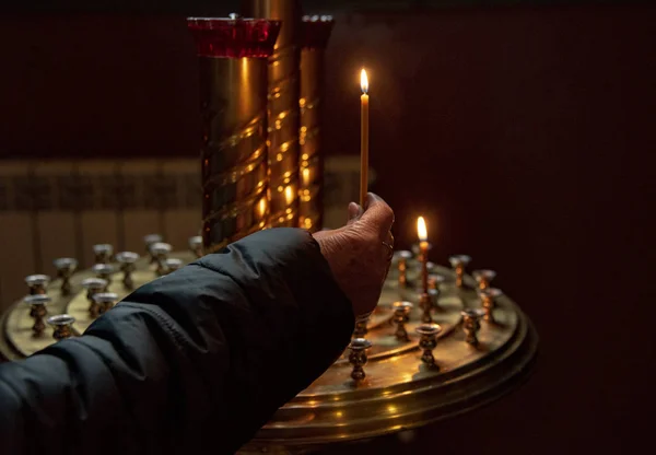 Candele di illuminazione a mano donna in una chiesa — Foto Stock