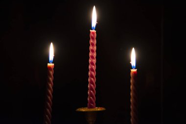  Three red candles burning in the darkness outside the window clipart