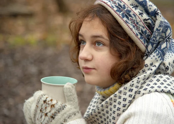 Молодая девушка в шляпе с рождественскими узорами и чашкой в руках — стоковое фото