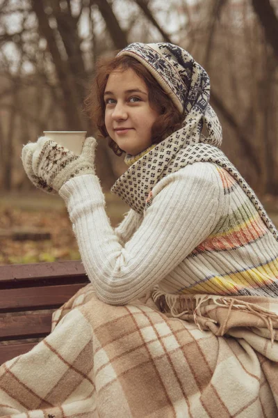 Menina com um chapéu engraçado bebendo de uma caneca na rua . — Fotografia de Stock