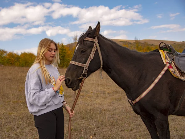 En ung flicka smeker försiktigt den bruna hästen — Stockfoto