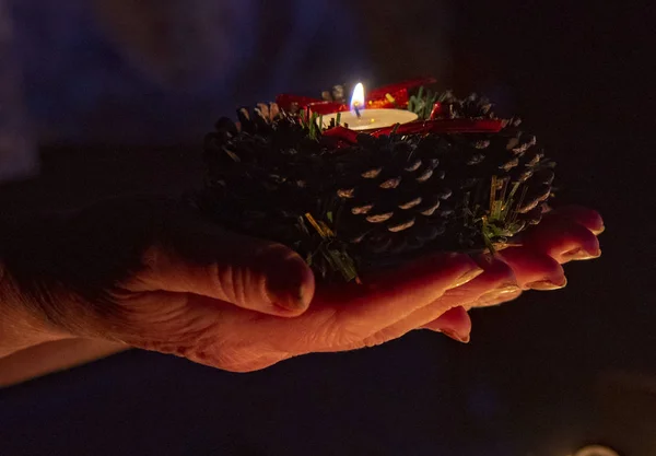 Burning candle on the palms of an elderly woman. — Stock Photo, Image