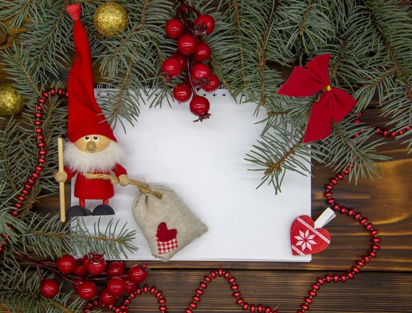 Sobre un fondo de madera, una hoja blanca de papel a su alrededor Decoración de Navidad . — Foto de Stock