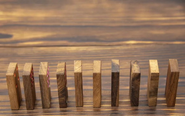 Domino chips placed on edge one after the other on a wooden table. — Stock Photo, Image