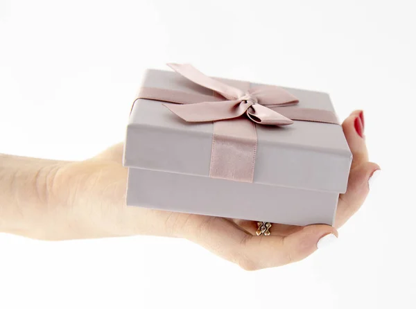 Female hand holds a gift box on a light background. Stock Photo