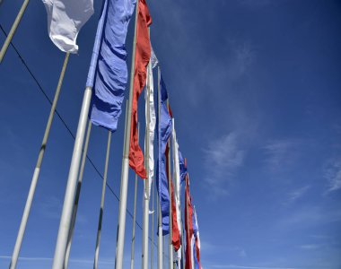 Mavi gökyüzüne karşı rüzgarda dalgalanan bayraklar.