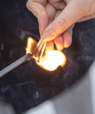 A womans hand with burning matches ignites sparklers.