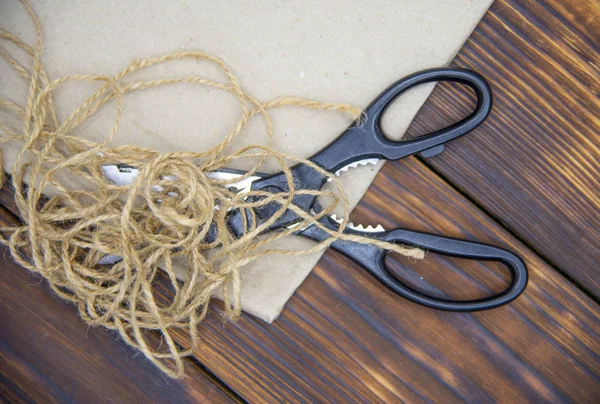 Tools for crafts on a wooden table top. Scissors, thread and paper. — Stock Photo, Image