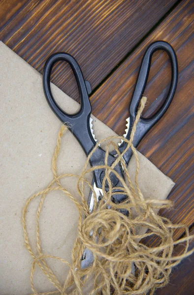 Tools for crafts on a wooden table top. Scissors, thread and paper. — Stock Photo, Image