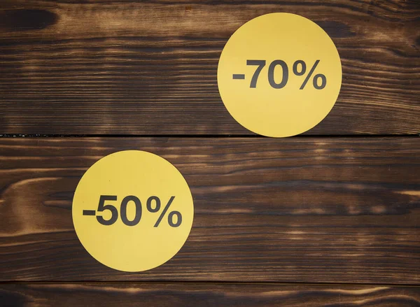 Yellow signs with discount percentages on a wooden background. — Stock Photo, Image