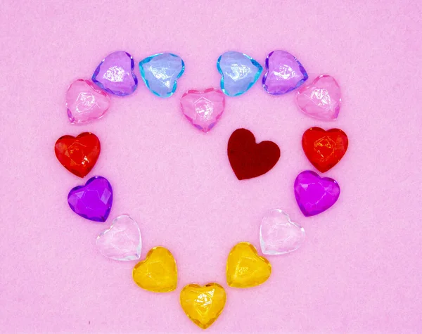 Small glass hearts are arranged on a pink background in the shape of one large heart. — 스톡 사진