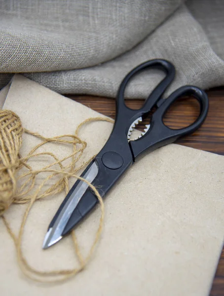 Herramientas para manualidades sobre una mesa de madera. Tijeras, hilo y papel . — Foto de Stock