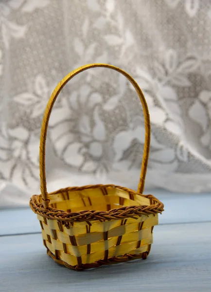 An empty wicker basket against a white lace curtain. — Stock Photo, Image