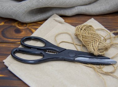 Ahşap bir masanın üstündeki el sanatları aletleri. Makas, iplik ve kağıt..