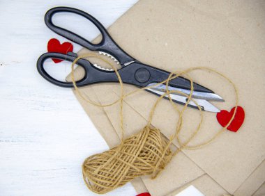 Makas, kabataslak iplik Kraft kağıdının üzerinde hafif ahşap bir arkaplanda yatıyor.