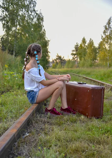 Een tienermeisje zit met een koffer op het spoor.. — Stockfoto