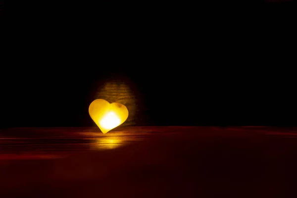 Un corazón amarillo brillante sobre un fondo oscuro . — Foto de Stock