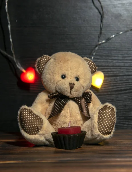 Soft toy bear and garland with hearts on a dark background. — Stock Photo, Image