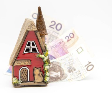 Red ceramic house on a blurred background of Polish banknotes.