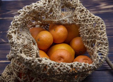 Top view of fresh oranges in string bag over old wooden rustic background.