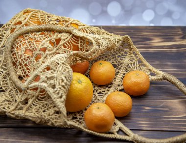 Parlak portakallar ve mandalinalar yeniden kullanılabilir bir alışveriş poşetinde, çevre dostu malzemelerden yapılır..