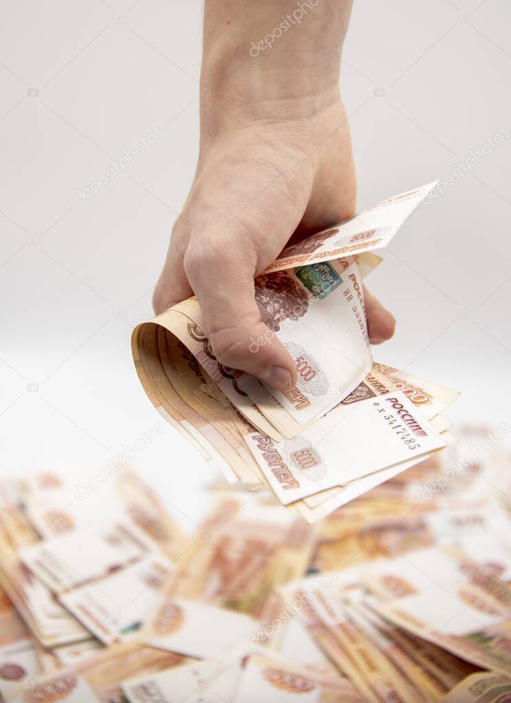 A man holds a stack of five-thousand-ruble bills in the palm of his hand 