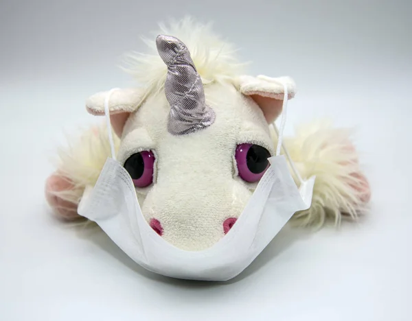 Tıbbi maskeli yumuşak oyuncak tek boynuzlu at. Enfeksiyona karşı bir ilacın kavramsal fotoğrafı. — Stok fotoğraf