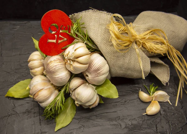 Un beau bouquet d'ail frais avec des feuilles de laurier et un cœur en bois.Enveloppé dans un tapis grossier et attaché avec Linden bast . — Photo