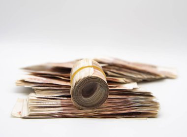 A pile of five-thousand-ruble bills and several banknotes twisted into a roll and tied with an elastic band.  clipart