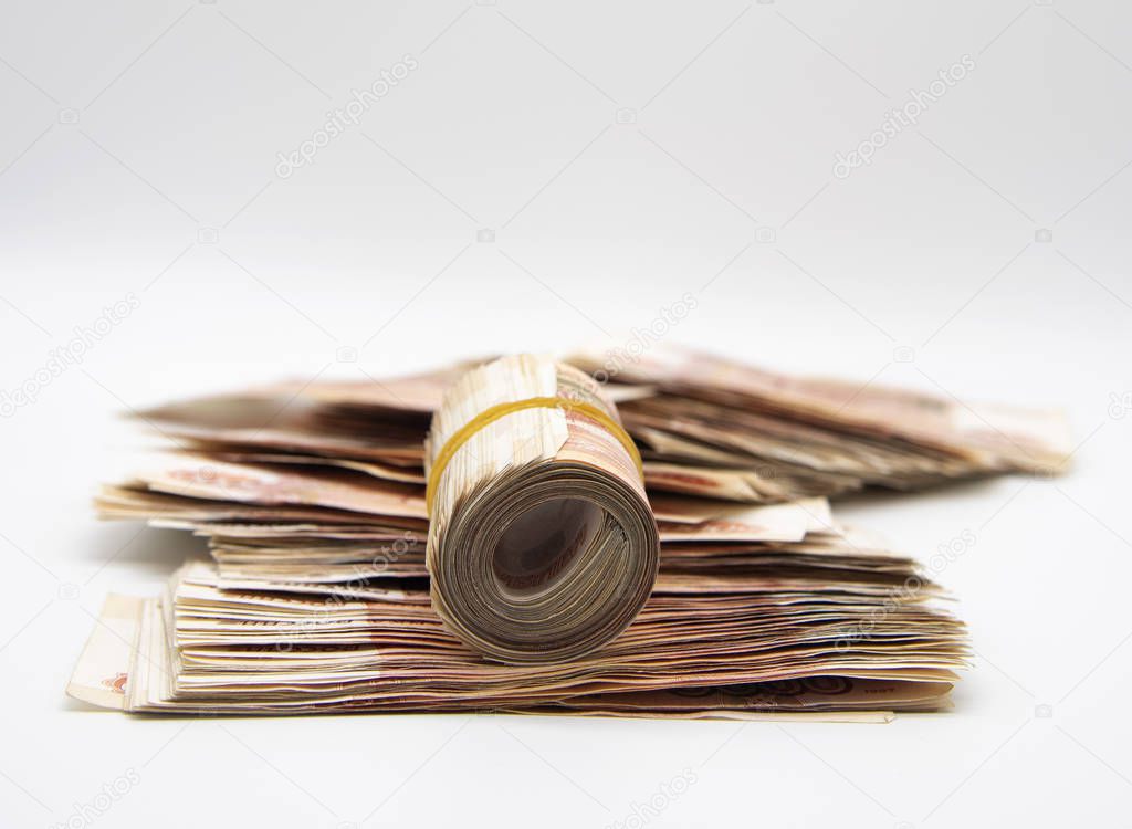 A pile of five-thousand-ruble bills and several banknotes twisted into a roll and tied with an elastic band. 
