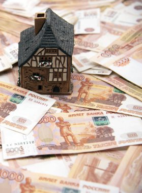 Bir seramik ev beş bin rublelik banknotların üzerinde duruyor. Başarı sembolü, yaşam koşullarının iyileştirilmesi
