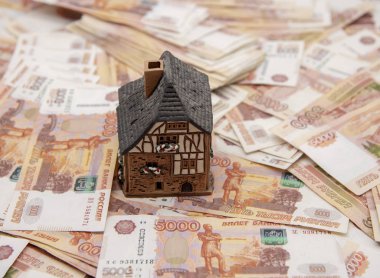 Bir seramik ev beş bin rublelik banknotların üzerinde duruyor. Başarı sembolü, yaşam koşullarının iyileştirilmesi