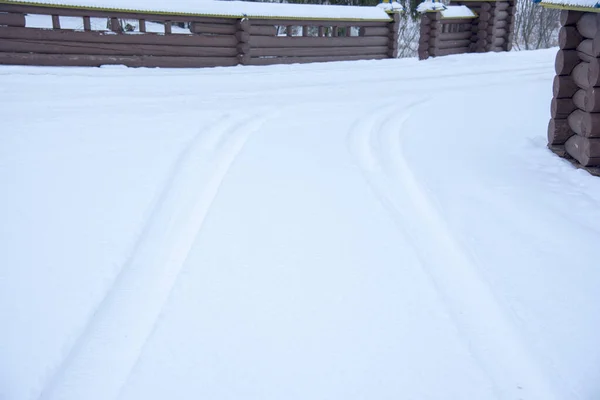 Sneeuwweg Met Voetafdrukken Van Wielen Tussen Houten Hekken — Stockfoto