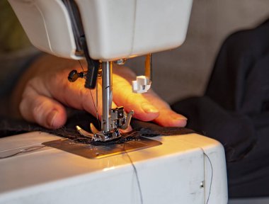 Dikiş makinesinde yaşlı kırışık kadınların elleri. Giysileri onarıyor. Seçici odaklanma..